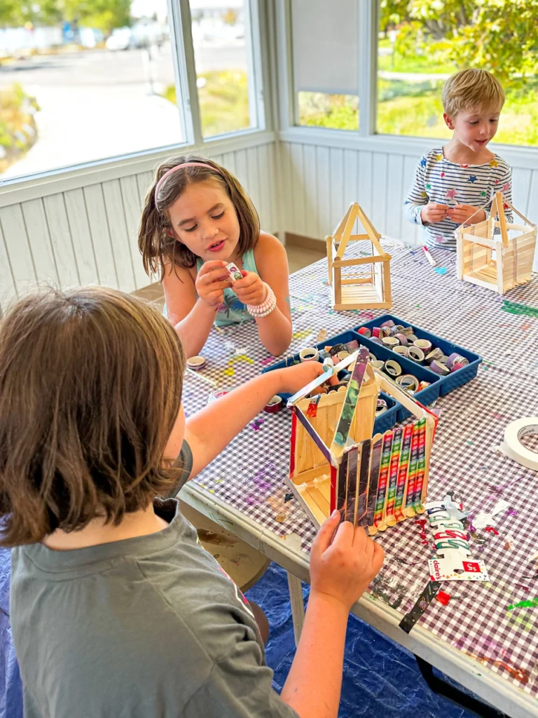 Campers building small wooden houses at a craft table