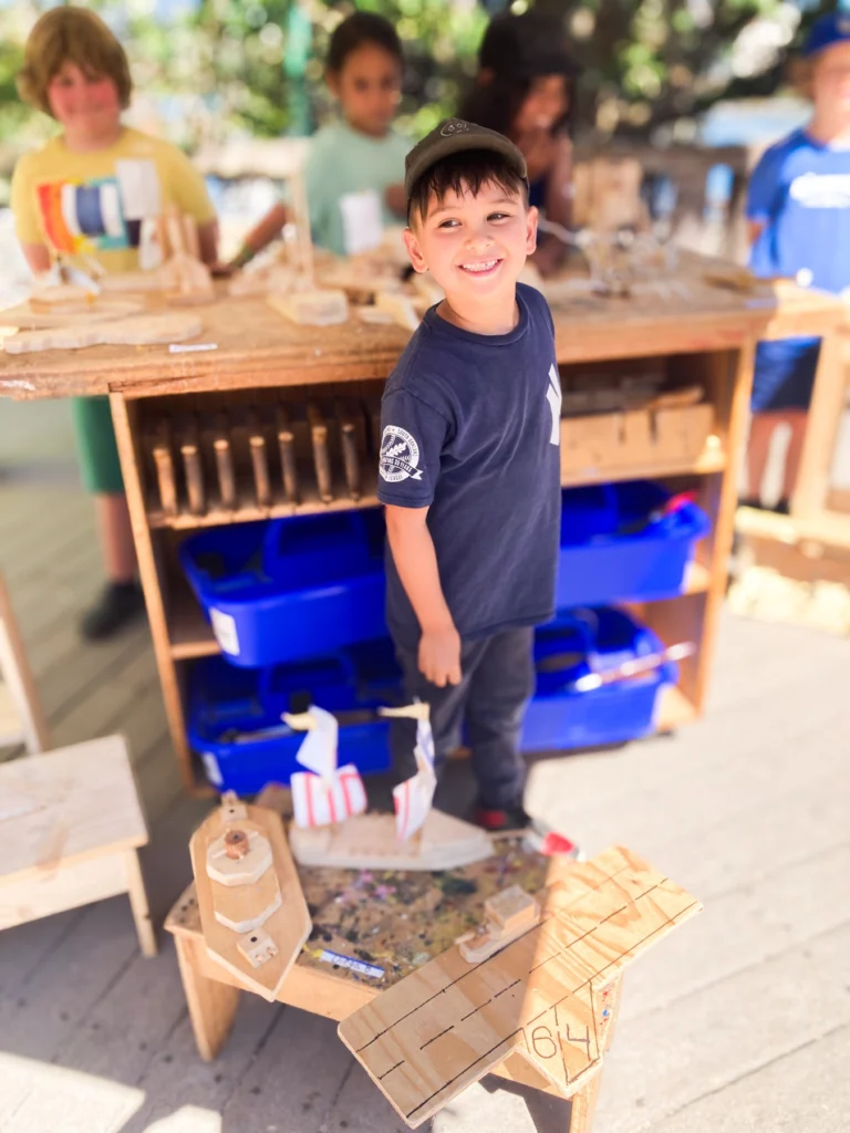 Camper smiling beside a woodworking station